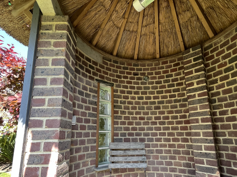 Brick hut with thatched roof.